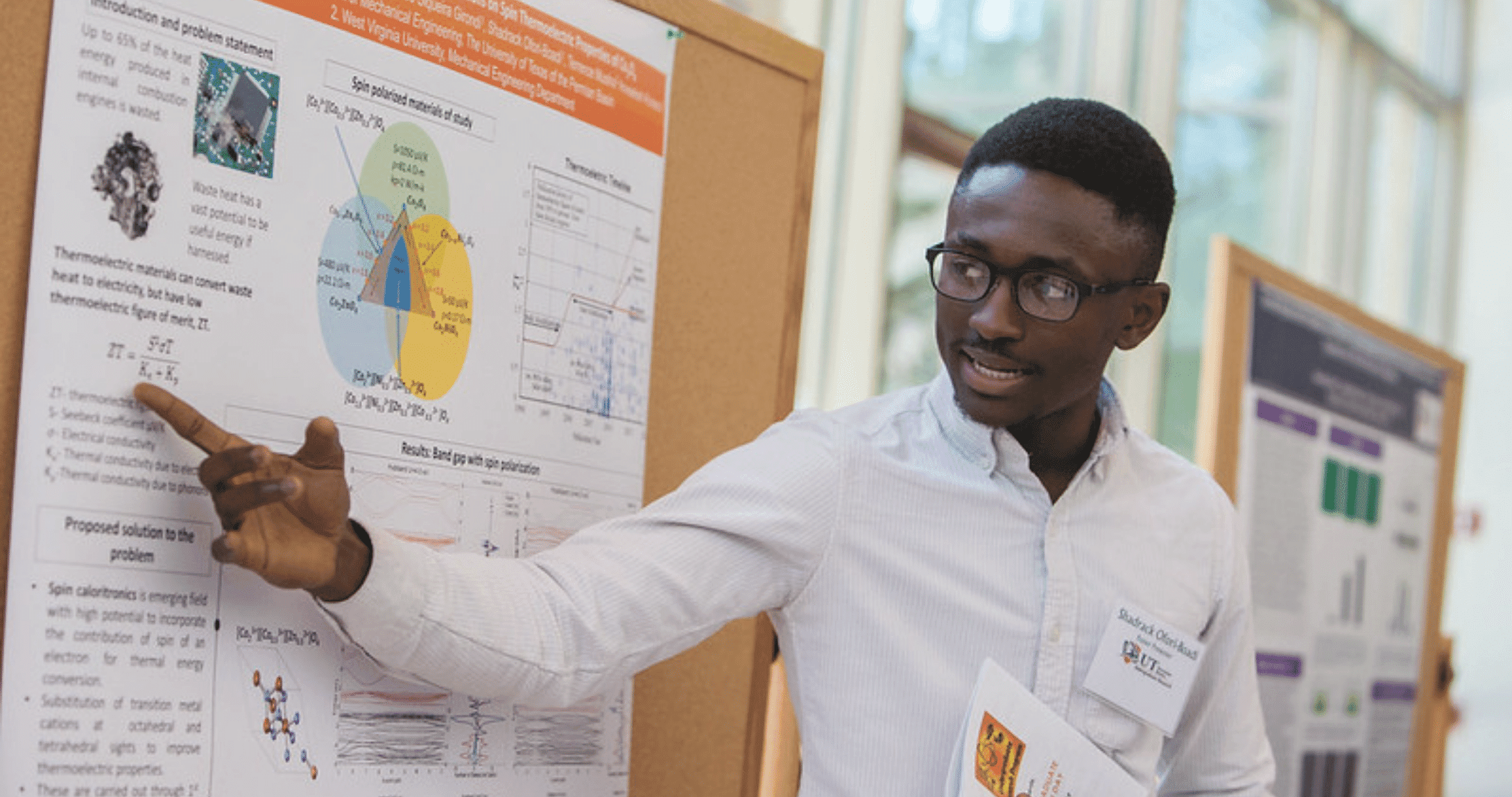 学生 pointing to research on board