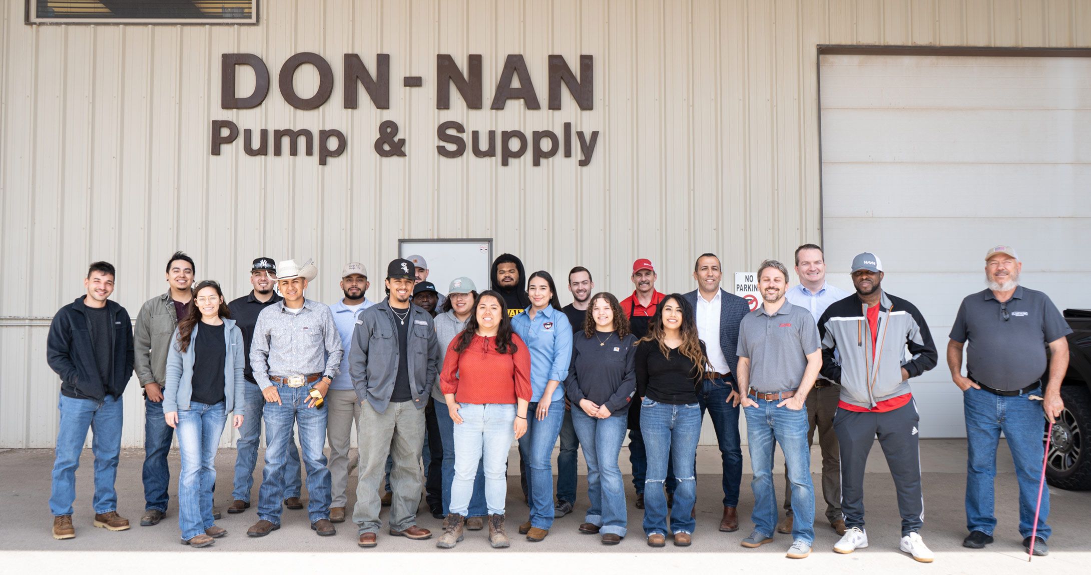 Petroleum engineering students smile in front of facility 