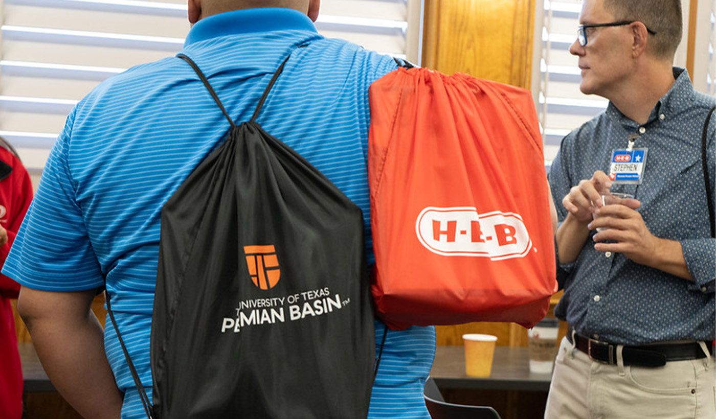 student holding utpb and heb backpack