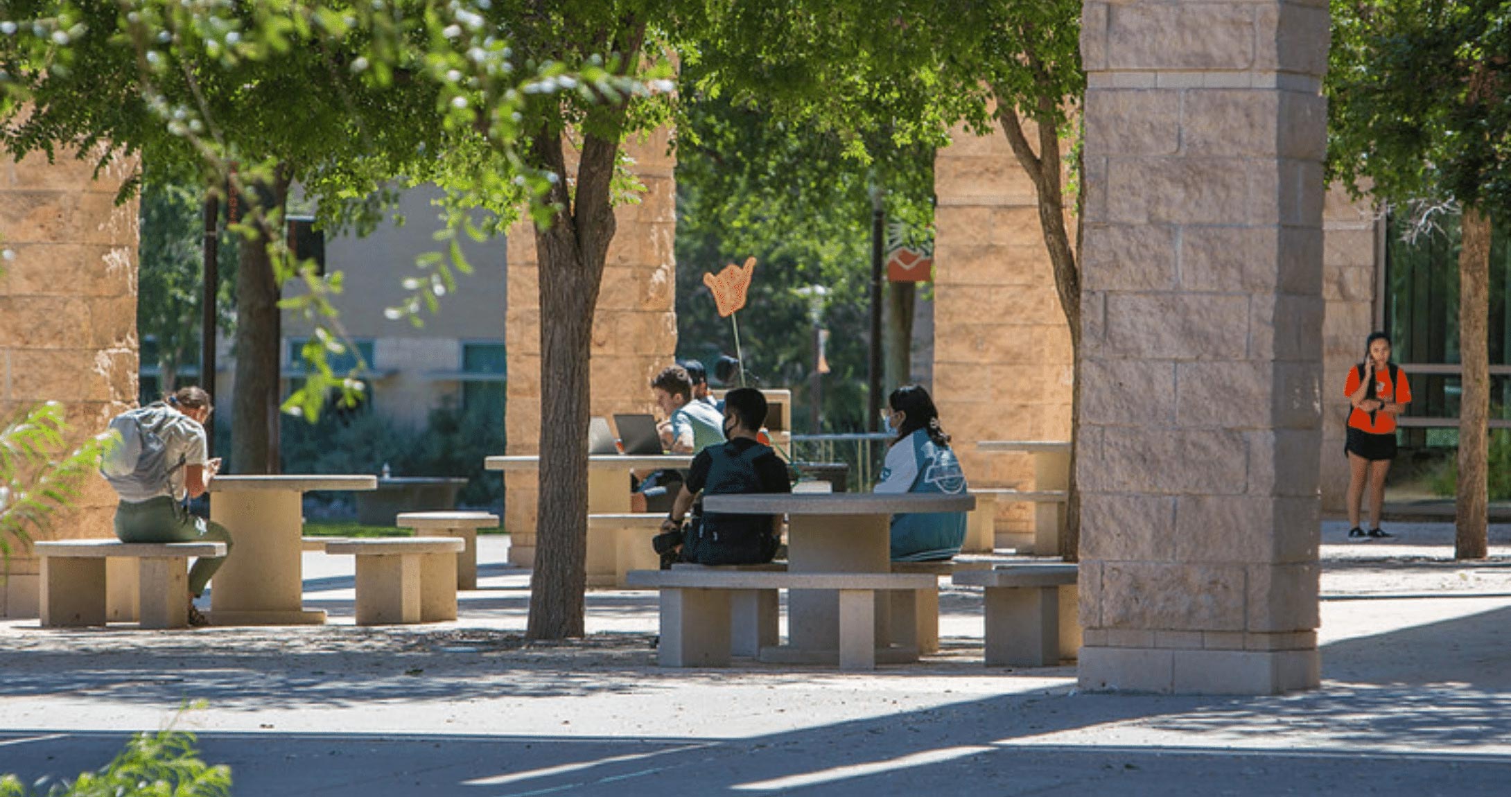 学生s sitting at picnic tables outside on campus