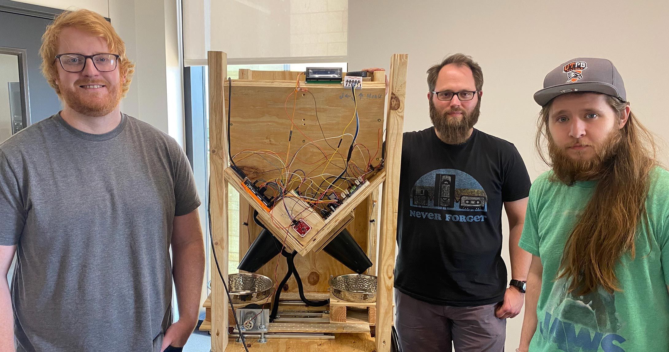 Electrical Engineering 学生s standing by automatic dog feeder