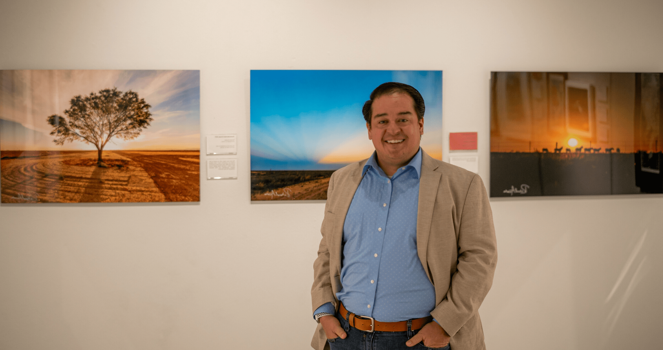 Staff member Richard Acosta stands in front of photos