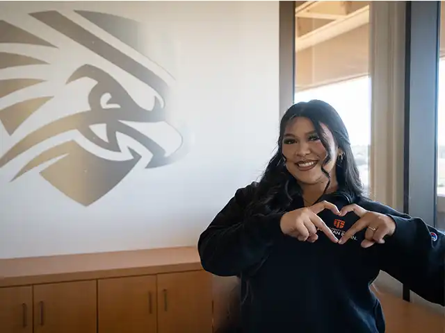 alumni making a heart with her hands